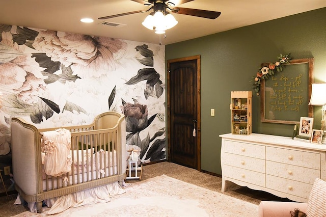 bedroom featuring carpet flooring, ceiling fan, and a nursery area