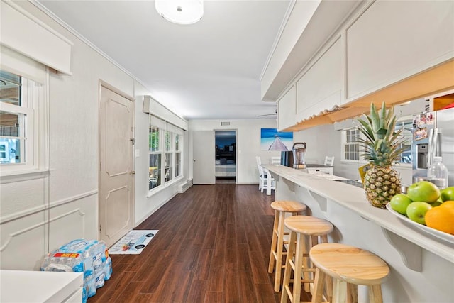 kitchen featuring a breakfast bar, dark hardwood / wood-style flooring, white cabinetry, and ornamental molding