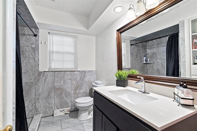 bathroom with vanity, toilet, curtained shower, and tile walls