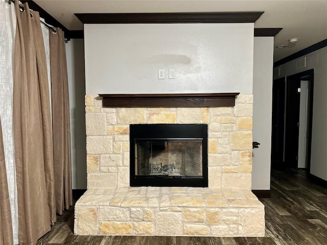 details with wood-type flooring, a stone fireplace, and crown molding