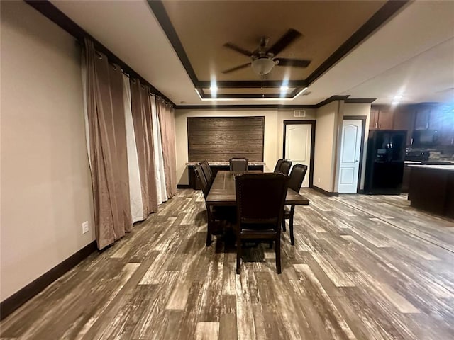 dining area featuring wood-type flooring, a raised ceiling, and ceiling fan