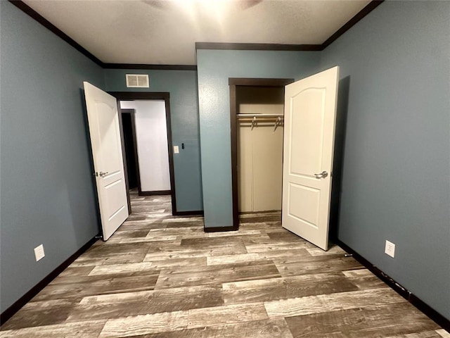 unfurnished bedroom featuring hardwood / wood-style flooring, a closet, and ornamental molding