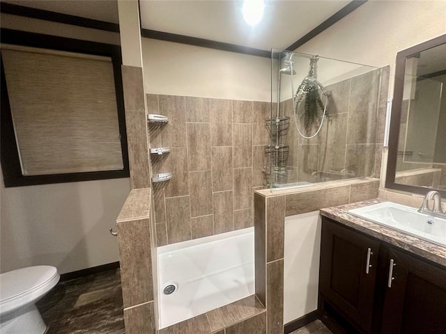 bathroom with toilet, vanity, and tiled shower