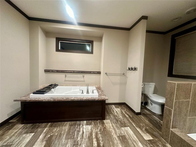 bathroom featuring hardwood / wood-style floors, a tub to relax in, toilet, and crown molding