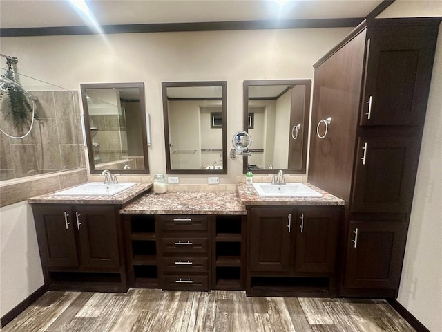 bathroom with hardwood / wood-style floors, vanity, and a tile shower