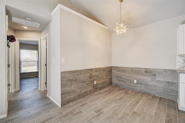 spare room featuring wood-type flooring, lofted ceiling, tile walls, and a notable chandelier