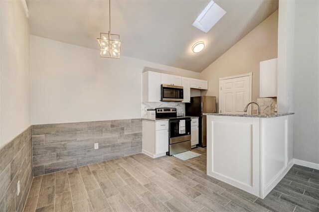 kitchen with a skylight, light wood-type flooring, appliances with stainless steel finishes, light stone counters, and white cabinetry