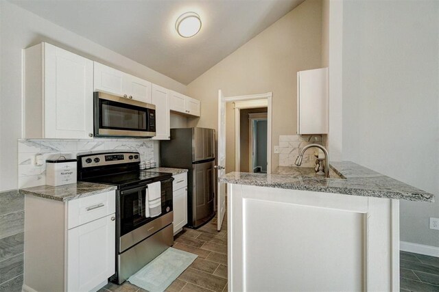 kitchen with kitchen peninsula, appliances with stainless steel finishes, and white cabinetry