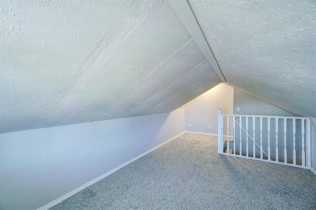 bonus room with a textured ceiling, carpet floors, and lofted ceiling