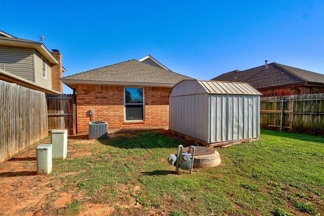 rear view of property with a yard, cooling unit, and a storage shed