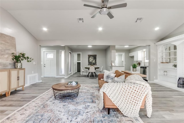 living room with light hardwood / wood-style flooring, ceiling fan, lofted ceiling, and sink