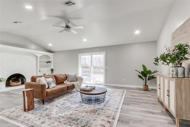 living room featuring ceiling fan, light hardwood / wood-style floors, a fireplace, and vaulted ceiling