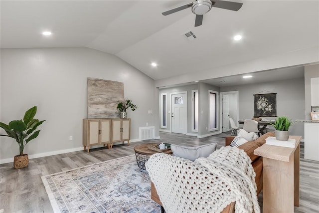 living room with ceiling fan, light hardwood / wood-style floors, and vaulted ceiling