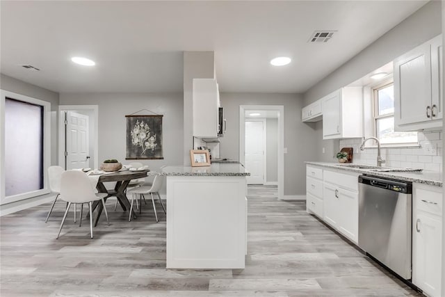 kitchen with light stone counters, dishwasher, white cabinets, and sink