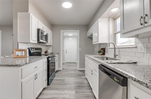 kitchen with appliances with stainless steel finishes, backsplash, white cabinetry, and sink