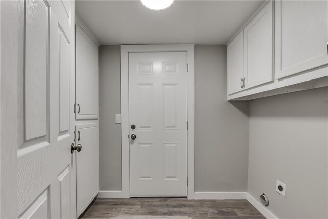 clothes washing area featuring hardwood / wood-style flooring, electric dryer hookup, and cabinets