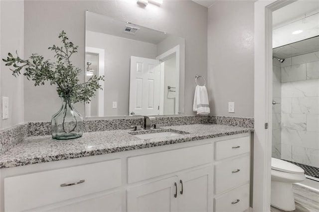 bathroom featuring vanity, toilet, and a tile shower