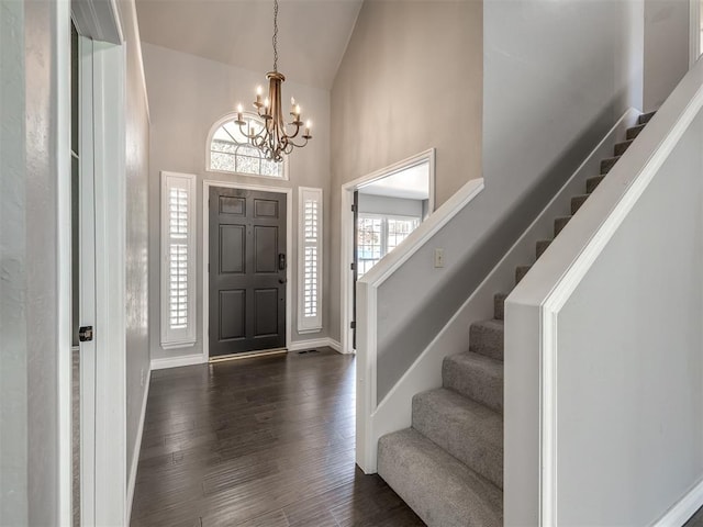 entrance foyer featuring a chandelier, high vaulted ceiling, and dark wood-type flooring