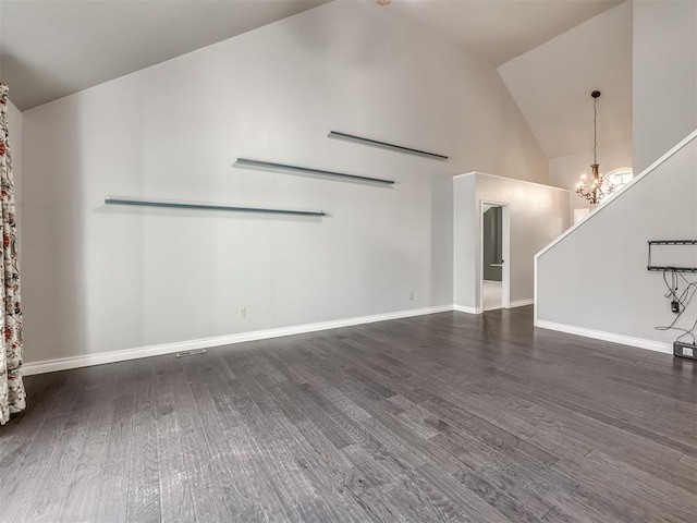 unfurnished living room with dark hardwood / wood-style flooring, high vaulted ceiling, and an inviting chandelier