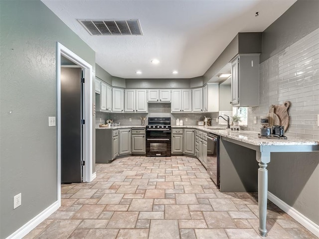 kitchen with dishwasher, black range oven, decorative backsplash, a kitchen bar, and kitchen peninsula