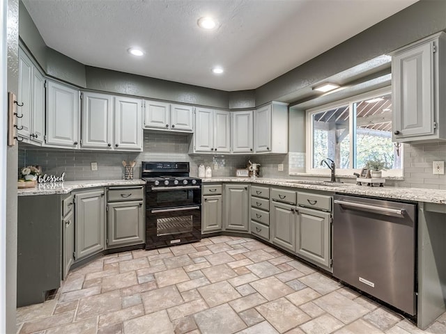 kitchen with gray cabinetry, dishwasher, backsplash, black range oven, and sink