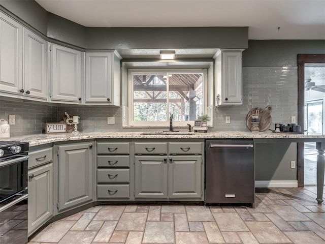 kitchen with tasteful backsplash, gray cabinetry, sink, and black range