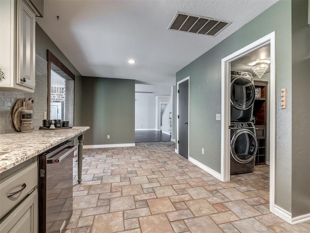 kitchen featuring dishwasher, stacked washing maching and dryer, and tasteful backsplash