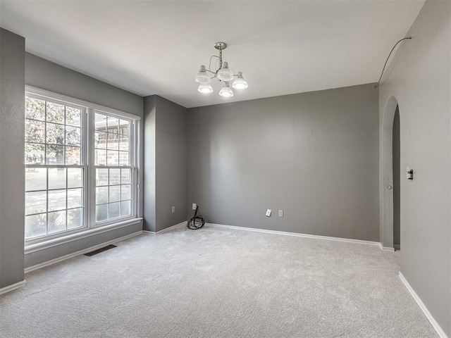 unfurnished room featuring light colored carpet and an inviting chandelier