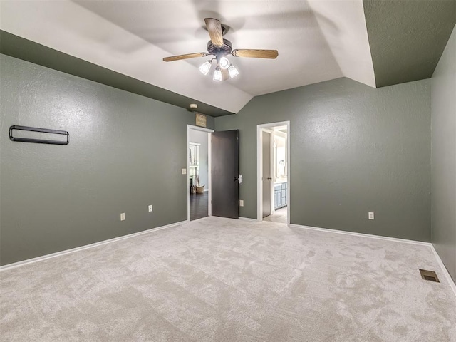 unfurnished bedroom featuring connected bathroom, ceiling fan, carpet floors, and vaulted ceiling