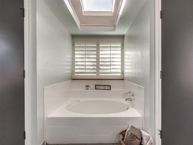 bathroom featuring a skylight and a washtub