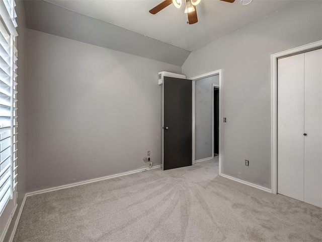 unfurnished bedroom featuring ceiling fan, light carpet, and vaulted ceiling