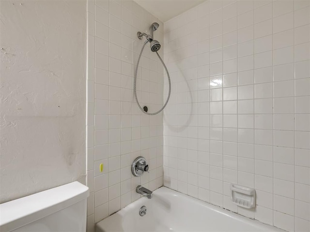 bathroom with tiled shower / bath combo and toilet