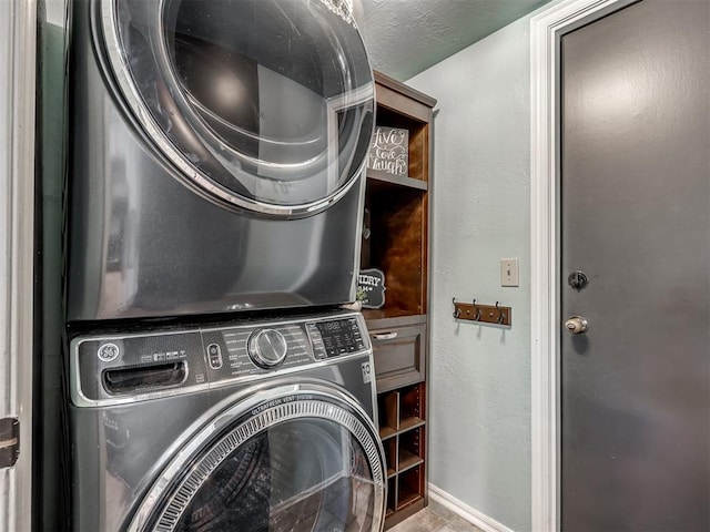 clothes washing area featuring a textured ceiling and stacked washer and clothes dryer