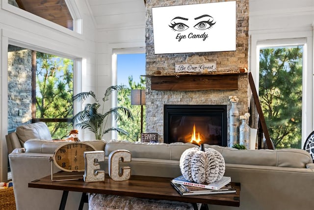 sitting room featuring vaulted ceiling, a stone fireplace, a healthy amount of sunlight, and wood ceiling