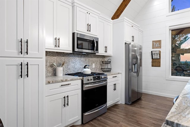 kitchen featuring white cabinets, wood walls, light stone countertops, and stainless steel appliances