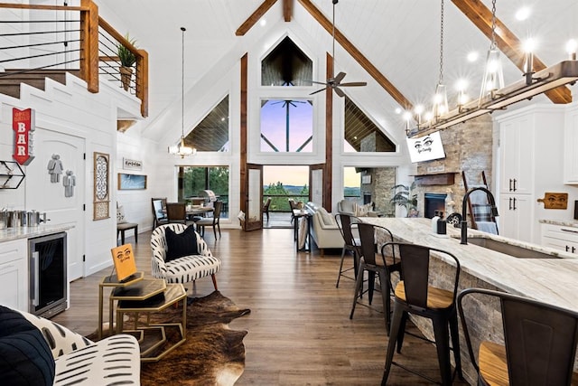 interior space with pendant lighting, high vaulted ceiling, light stone counters, white cabinetry, and beverage cooler