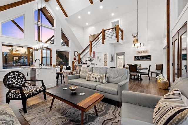 living room with high vaulted ceiling, an inviting chandelier, wooden walls, beam ceiling, and wood-type flooring