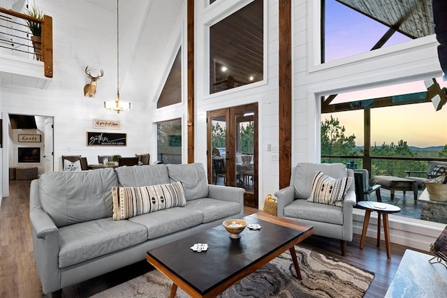 living room with hardwood / wood-style floors, wooden walls, high vaulted ceiling, and a chandelier