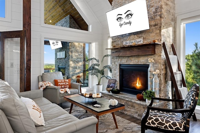 sitting room with a stone fireplace, high vaulted ceiling, and hardwood / wood-style flooring