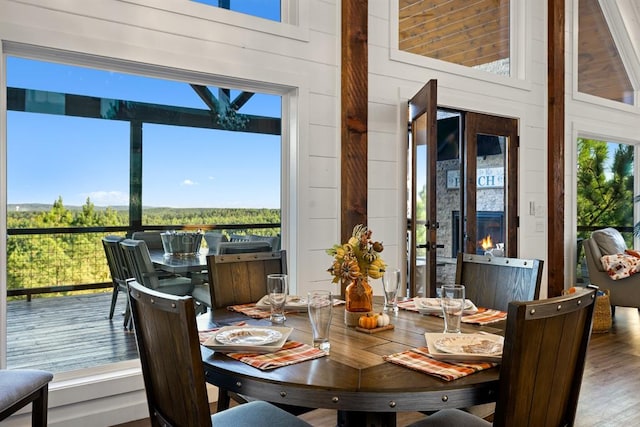 dining area featuring wood walls, hardwood / wood-style floors, and a high ceiling