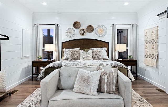 bedroom featuring a barn door, hardwood / wood-style floors, and ornamental molding