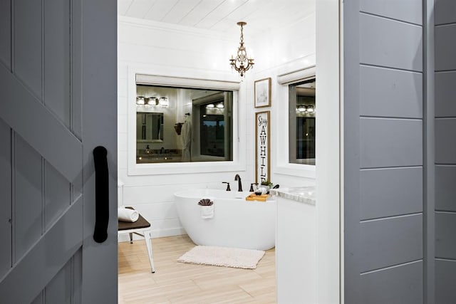 bathroom with wood-type flooring, a bathtub, and a notable chandelier