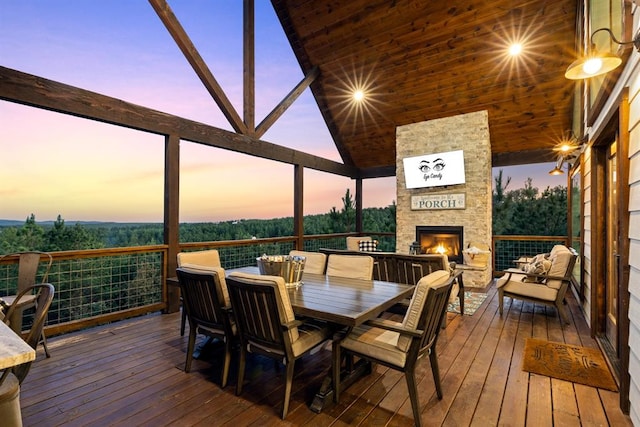 sunroom with lofted ceiling and an outdoor stone fireplace