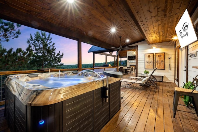 deck at dusk featuring ceiling fan and a hot tub