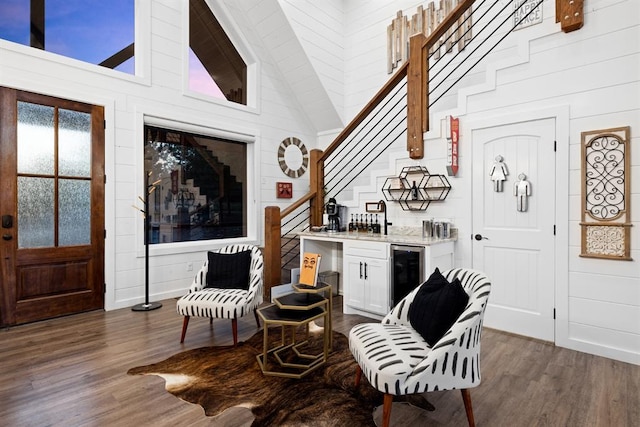 entryway featuring high vaulted ceiling, wooden walls, dark hardwood / wood-style floors, bar, and beverage cooler