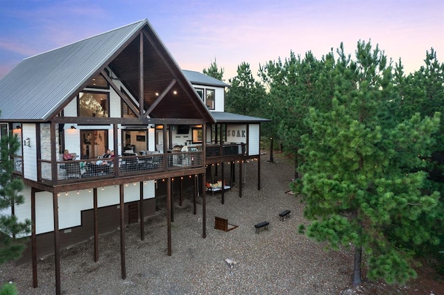 back house at dusk featuring a wooden deck