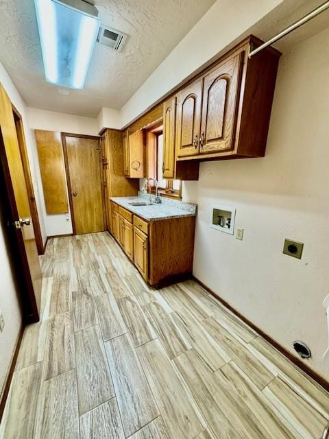 kitchen with a textured ceiling, light wood-type flooring, and sink