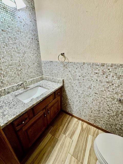 bathroom featuring vanity, tile walls, and toilet