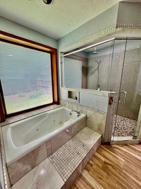 bathroom with plus walk in shower, a textured ceiling, and hardwood / wood-style flooring