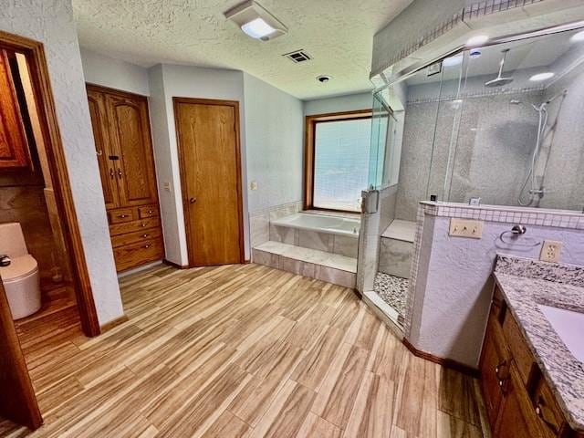 full bathroom featuring vanity, hardwood / wood-style floors, plus walk in shower, and a textured ceiling